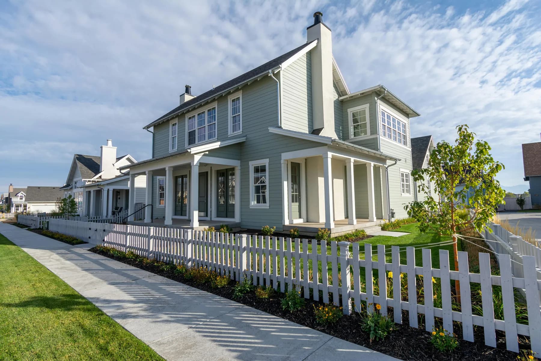 A two-story suburban family home with a white picket fence